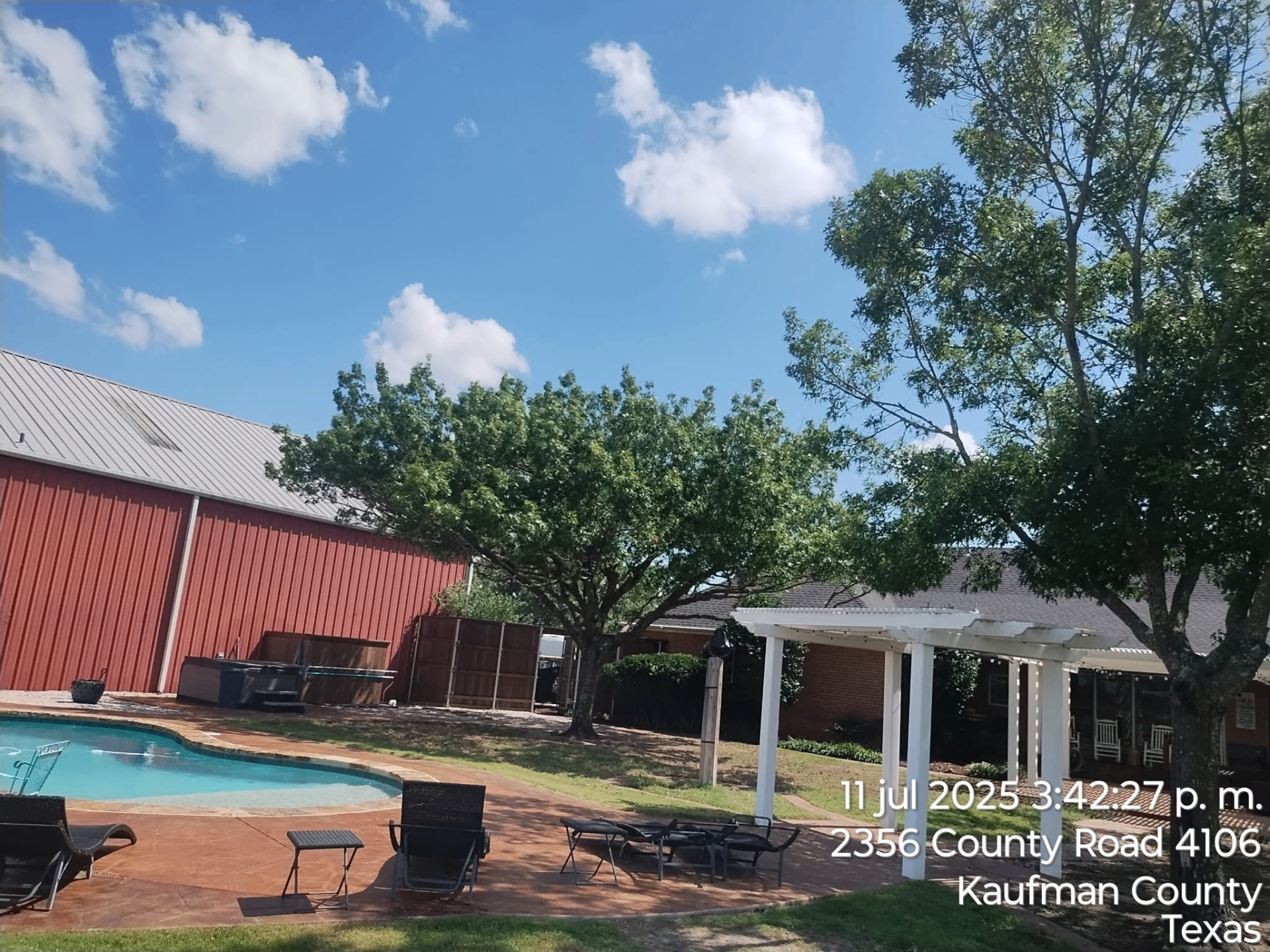 Backyard pool area with mature trees and hardscape