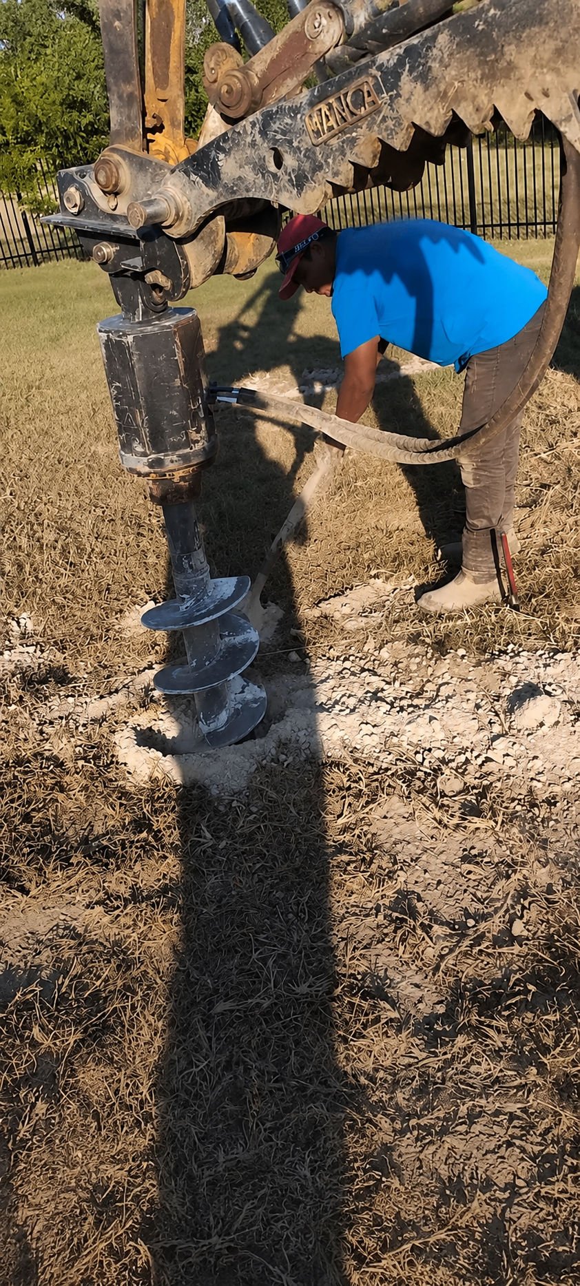 Auger drilling post holes for fence installation